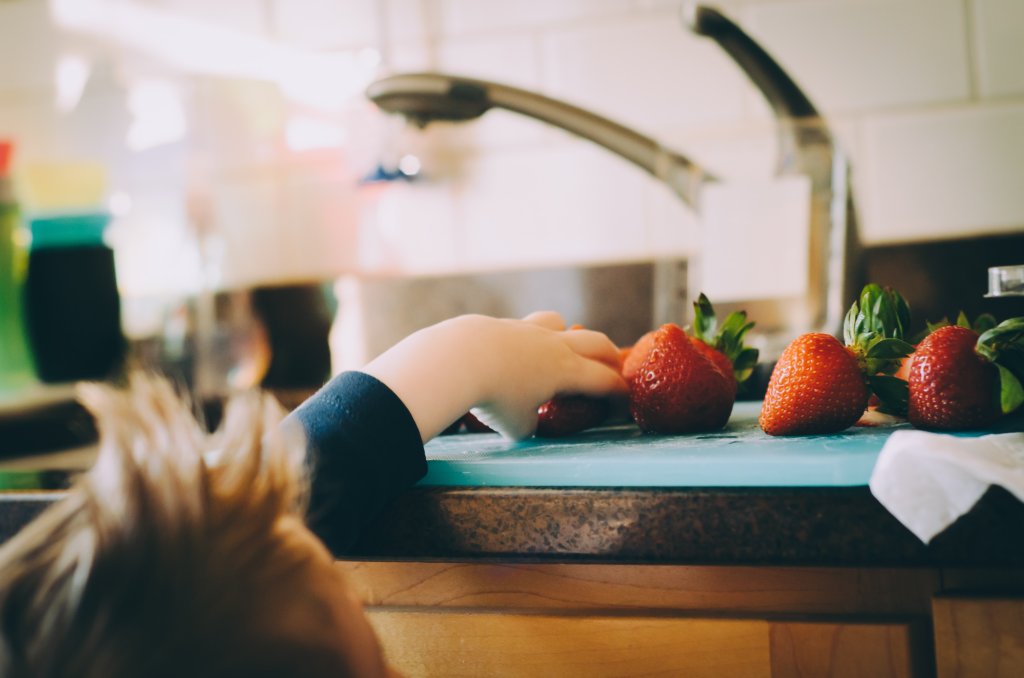 Child reaching for food on counter top. Photo by Kelly Sikkema on Unsplash.