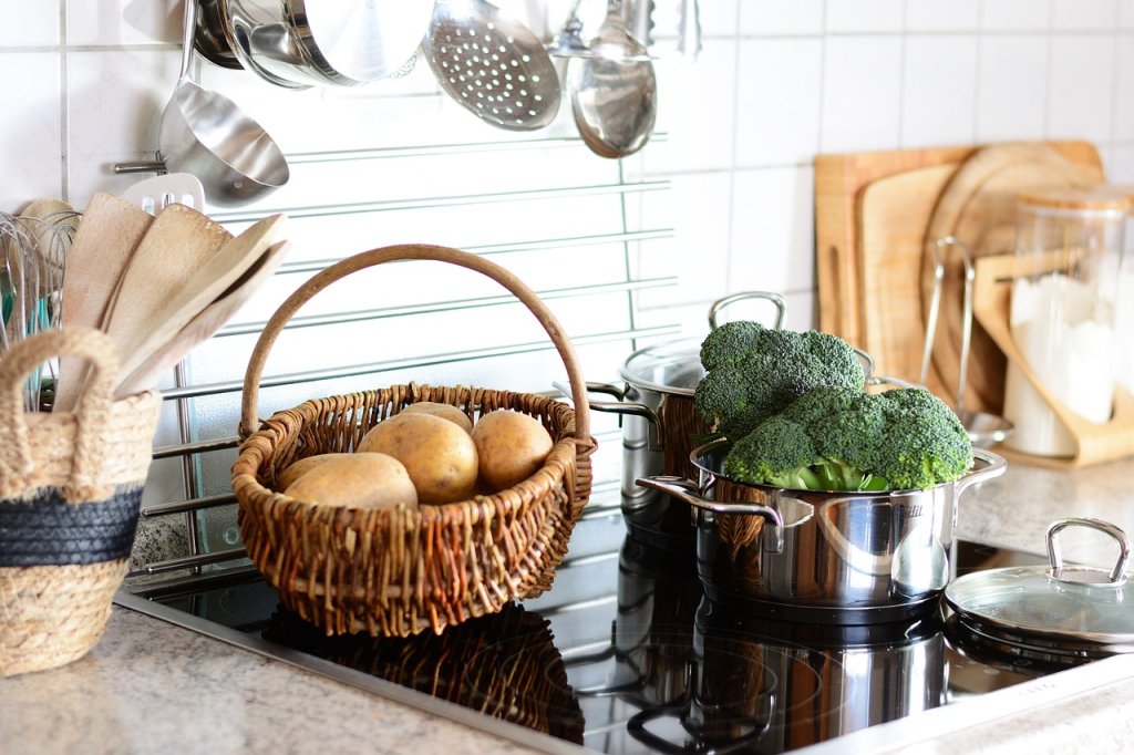 Kitchen countertop ceramic hood, with cooking pot of broccoli and basket of potatoes. Image by Conger Design from Pixabay.