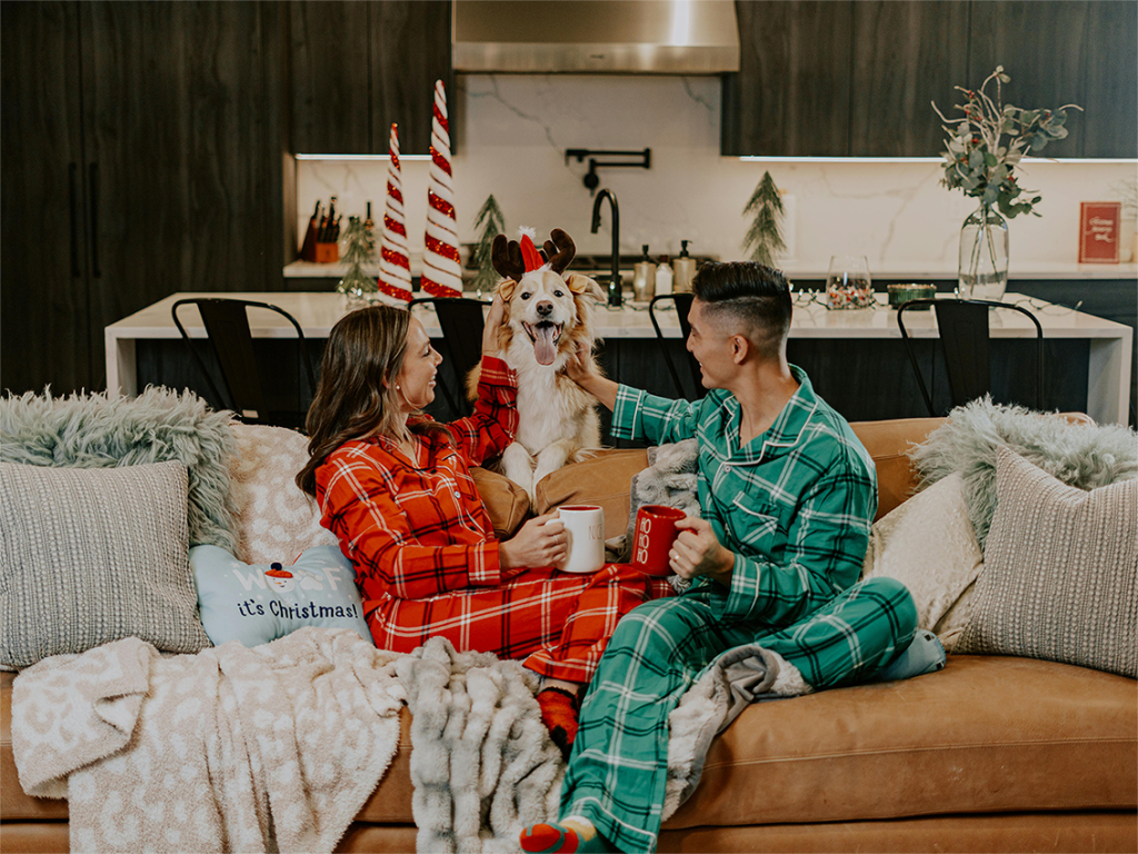 Cosy Christmas 2024 couple in matching pyjamas, with a dog in an antler hat by Impact Dog Crates on Pexels.